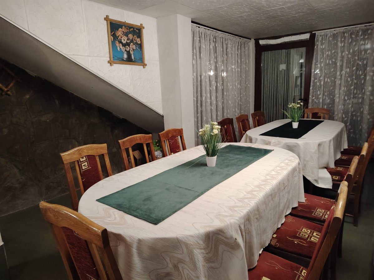 Подредени маси с бели покривки в голямата механа
